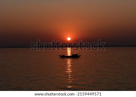 Setting sun makes a graceful view with dingy boat on Meghna river