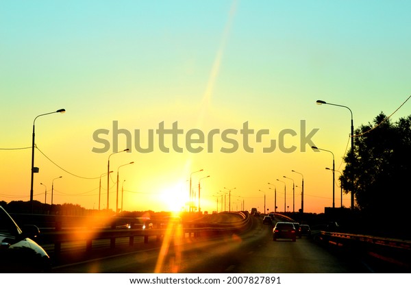 Setting sun on an asphalt road. The setting sun in a\
stream of cars