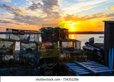 The Setting Sun From A Pier On The Passamaquoddy Bay In Lubec, Maine, Piled With Lobster Fishing Paraphernalia 