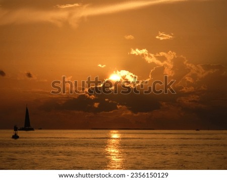 Setting sun is sinking behind clouds over the ocean.