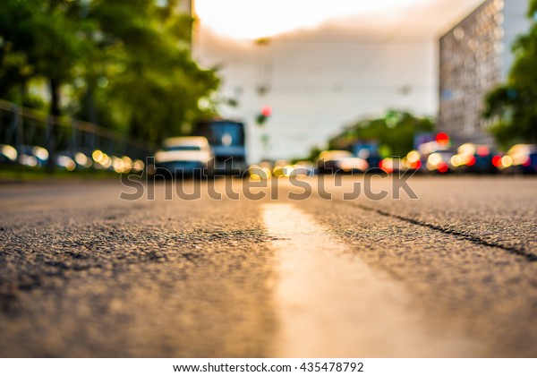Setting sun in the\
suburbs, stream of cars traveling on the road. View from the level\
of the dividing line