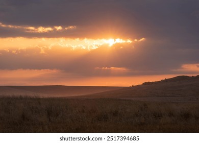 The setting sun through the clouds and reflections on the hills
