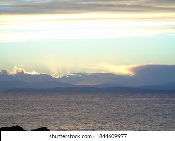 Setting suns rays shine out from behind the evening clouds into the twilight sky