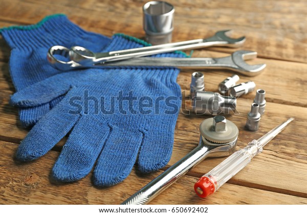 Setting of tools for car repair and gloves on\
wooden background
