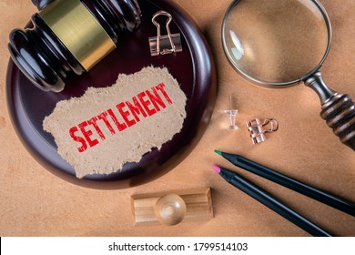 SETTLEMENT. Laws, litigation, lawyers and compromise concept. Wooden court hammer and magnifying glass on the table