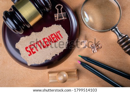 SETTLEMENT. Laws, litigation, lawyers and compromise concept. Wooden court hammer and magnifying glass on the table Stock foto © 