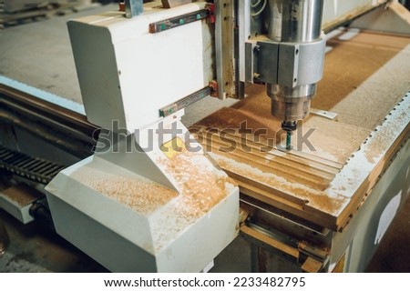 Setup of CNC machine in a factory. Focus on a CNC machine while working and making pattern in a wooden furniture in a factory. Copy space.