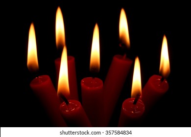 seven burning candles on black background