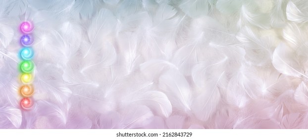 Seven Chakras feather message banner background - pink purple turquoise green yellow orange red vortex energy chakra centres stacked on left side against pale fluffy white feather background  - Shutterstock ID 2162843729