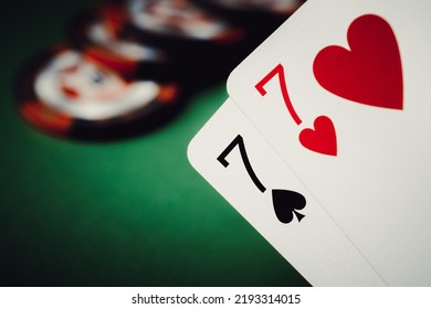 Seven of hearts and seven of spades. A pair of sevens and poker chips on a green background, poker background. 