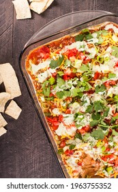 Seven Layer Bean Dip And Tortilla Chips On A Dark Wooden Background