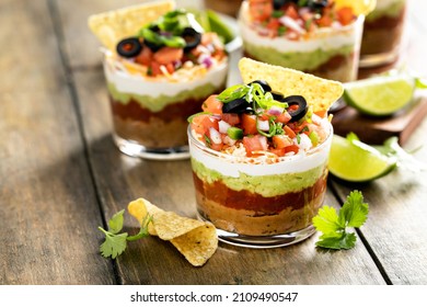 Seven layer dip in individual cups, mexican appetizer with refried beans, salsa, guacamole - Shutterstock ID 2109490547