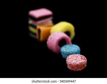 Seven liquorice allsorts candy isolated on black background, one in focus and the rest out of focus