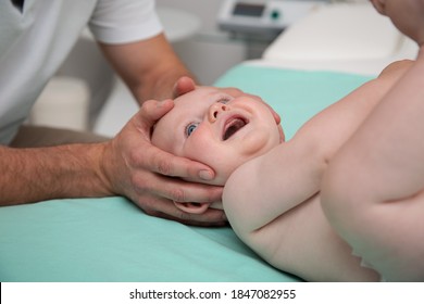 Siebmonatiger Babykopf wird von Osteopathie-Handtherapeuten oder Ärzten manipuliert. Arzt-Massage-Kopf kleiner Kaukasier-Baby-Junge
