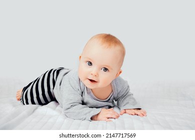 Seven month old baby child sitting on bed. Cute smiling little infant girl on white soft blanket. Charming blue eyed baby. Copy space. - Shutterstock ID 2147717569