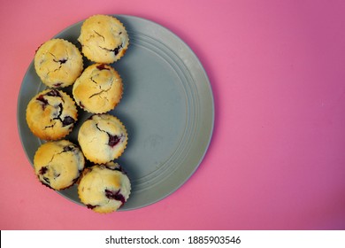 Seven Muffins Made From Rice Flour, Yogurt And Cherries Lie On A Round Gray Plate On A Pink Background Top View.  Homemade Gluten Free Baked Goods