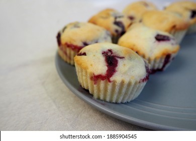 Seven Muffins Made From Rice Flour, Yogurt And Cherries Lie On A Round Gray Plate On A Beige Tablecloth Side View.  Homemade Gluten Free Baked Goods