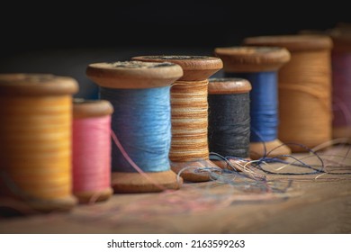 Seven old wooden spools of thread in different colors in retro and vintage style in soft contrasted light
