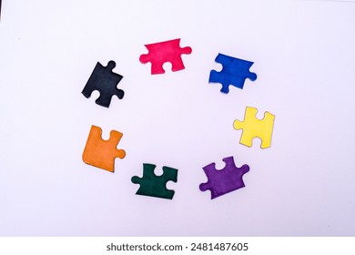 Seven puzzle pieces scattered on a white surface. This image could be relevant for discussions or individuality within a group