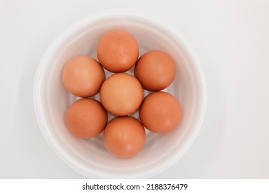 Seven Raw Chicken Eggs In A Styrofoam Cup With White Background.