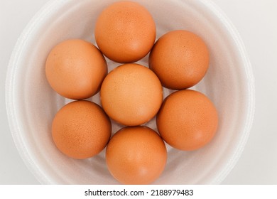 Seven Raw Chicken Eggs In A Styrofoam Cup With White Background.