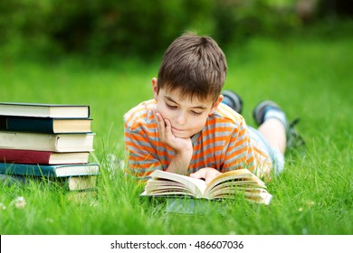 seven years old child reading a book lying on the grass