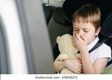 Seven Years Old Small Child In The Backseat Of A Car Sitting In Children Safety Car Seat Covers His Mouth With His Hand - Suffers From Motion Sickness