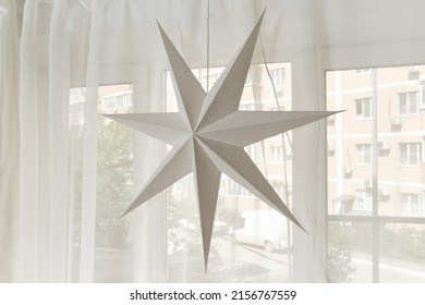 a seven-pointed star made of cardboard hangs by the window - Powered by Shutterstock