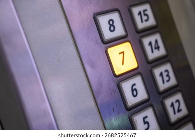 The seventh floor button in an elevator, illuminated with orange light on a gray metallic panel