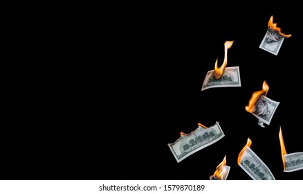 Several 100 dollar bills, falling down, burn on a black background. The concept of bankruptcy, depreciation, devaluation, wastefulness and waste of money. Copy space, isolated.