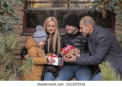 Several Adult Family Members Give Presents To A Cute Little Boy Outside