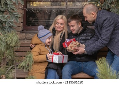 Several Adult Family Members Give Presents To A Cute Little Boy Outside