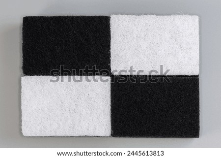Several black and white kitchen soft synthetic cleaning sponges laid out hard urethane abrasive layer up on a gray background, top view

