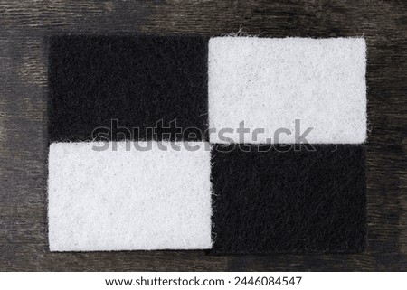 Several black and white kitchen soft synthetic cleaning sponges laid out hard urethane abrasive layer up on a black surface, top view

