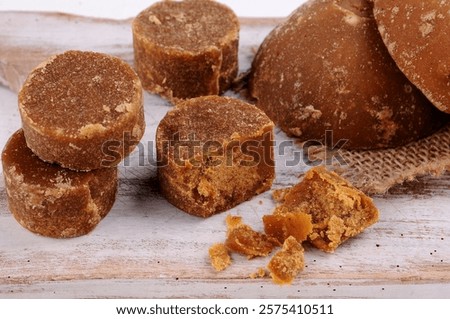 several blocks and chunks of brown sugar or gula jawa, some whole and some cut, scattered on a wooden surface