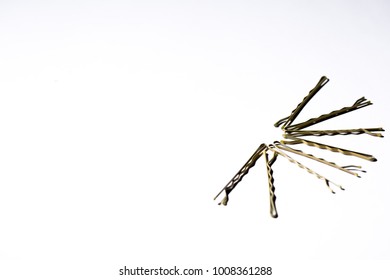several bobby pins laid out on a white background forming a half circle 