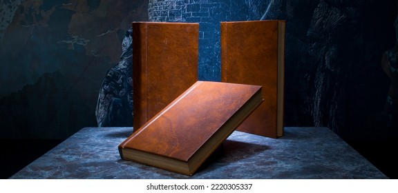 several books with the same binding on a dark background isolated. three books with a brown cover without inscriptions and titles with free space for text