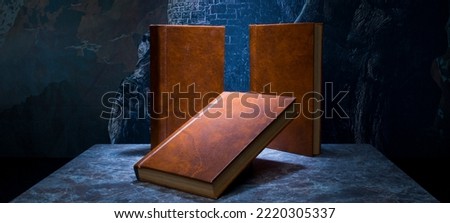 several books with the same binding on a dark background isolated. three books with a brown cover without inscriptions and titles with free space for text