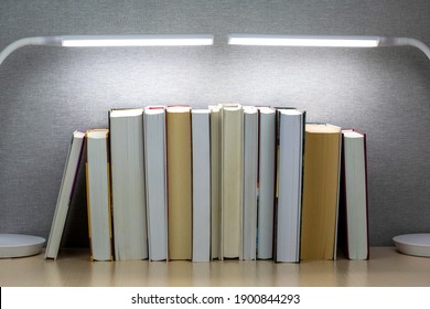 Several Books Stand On The Table Under Table Lamps.