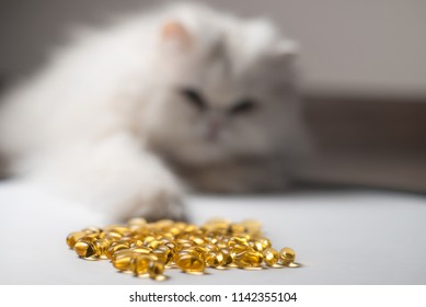 Several Capsules Of Fish Oil. Curious Cat In The Background. White And Yellow Colors