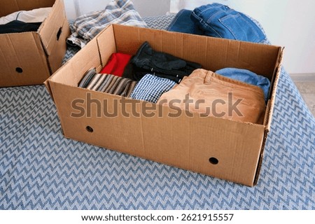Several cardboard boxes for donations with things. Winter and summer clothes. Help for the poor and needy people.