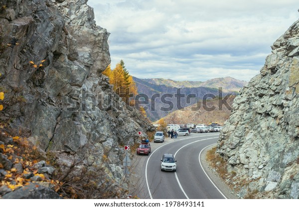 Several cars parked by mountain highway between\
rocks in autumn colors. Cars on mountain pass and autumn leaves on\
rocks. Russia, Altai Republic, Chuysky tract, Chike-Taman pass, 19\
September, 2020.