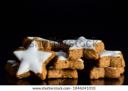 Several Christmas cookies, so-called cinnamon stars, are stacked against a dark background