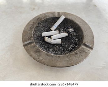 several cigarette butts in the ashtray. Cigarettes can cause cancer, heart attacks, impotence and fetal pregnancy problems. - Shutterstock ID 2367148479