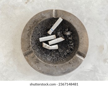 several cigarette butts in the ashtray. Cigarettes can cause cancer, heart attacks, impotence and fetal pregnancy problems. - Shutterstock ID 2367148481