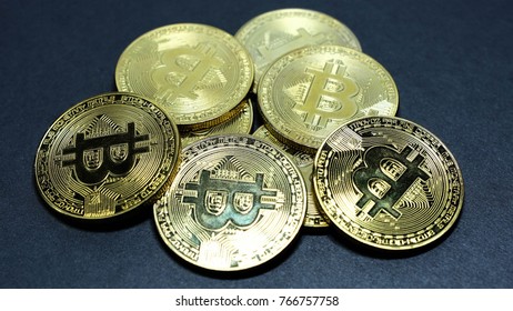 several coins of gold bitcoins on a dark background.