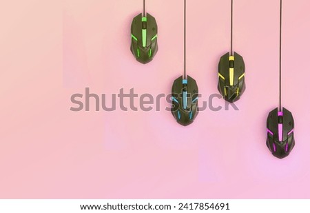 Several computer mice hang on a pastel pink background. The concept of cooperative computer video games, the use of auto-clicker and pay-per-click platforms. Flat lay with copy space