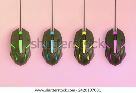 Several computer mice hang on a pastel pink background. The concept of cooperative computer video games, the use of auto-clicker and pay-per-click platforms. Flat lay abstract minimal composition