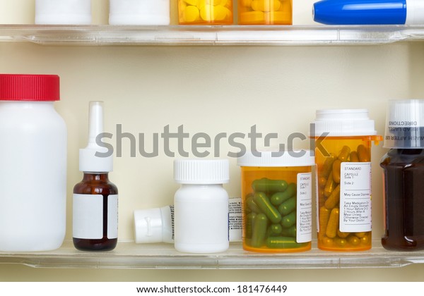 Several containers\
of over the counter and prescription medications on the shelves of\
a 1960\'s medicine cabinet.\
