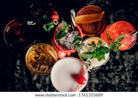several different beautiful colorful cocktails on a dark background. top view